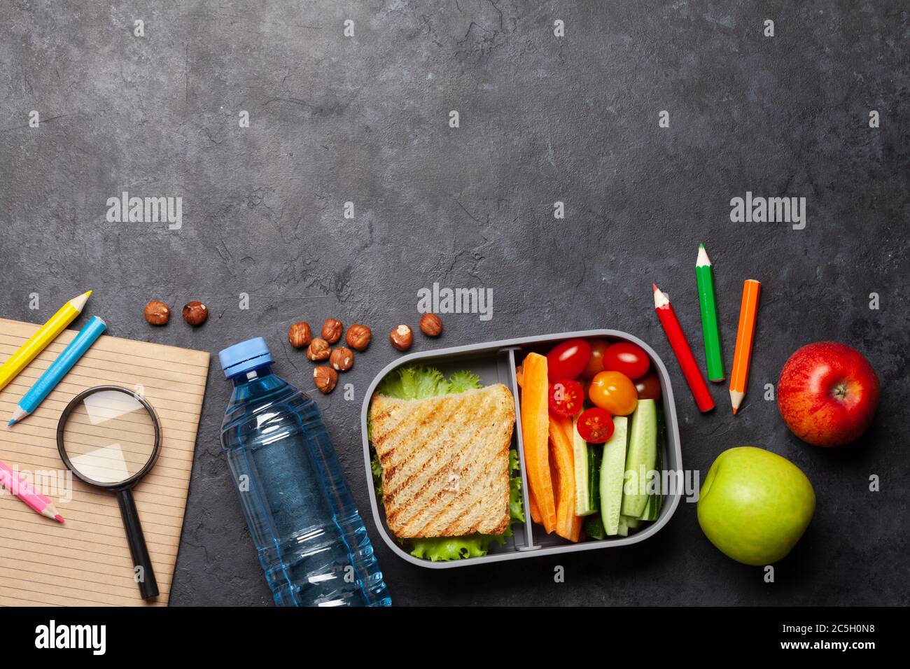 School lunch box and education stationery on stone table. Top view with ...