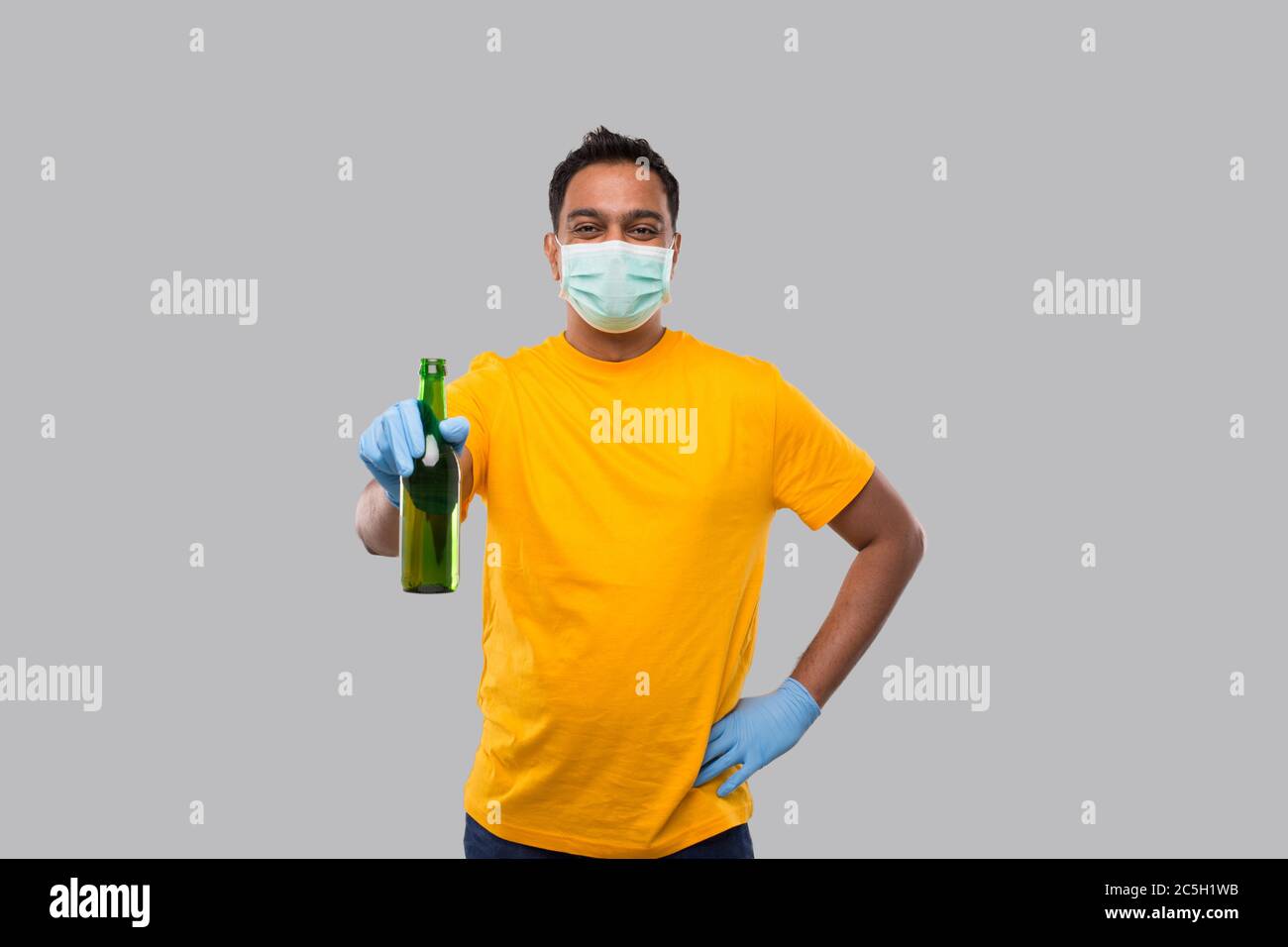 Indian man Holding Beer bottle Wearing Medical Mask and Gloves Isolated. Stock Photo
