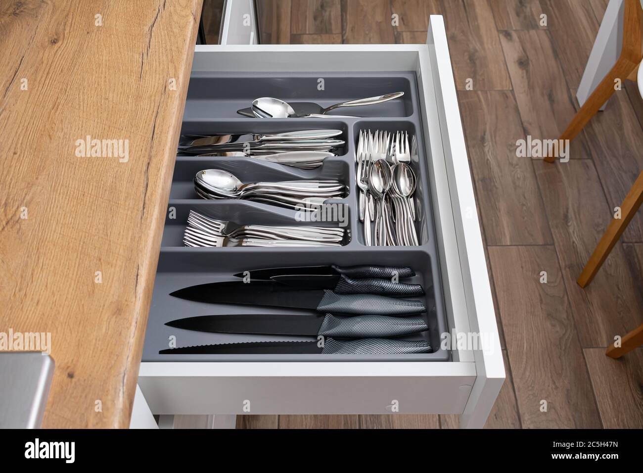 Stainless steel cutlery set in drawer. Opened kitchen drawer Stock