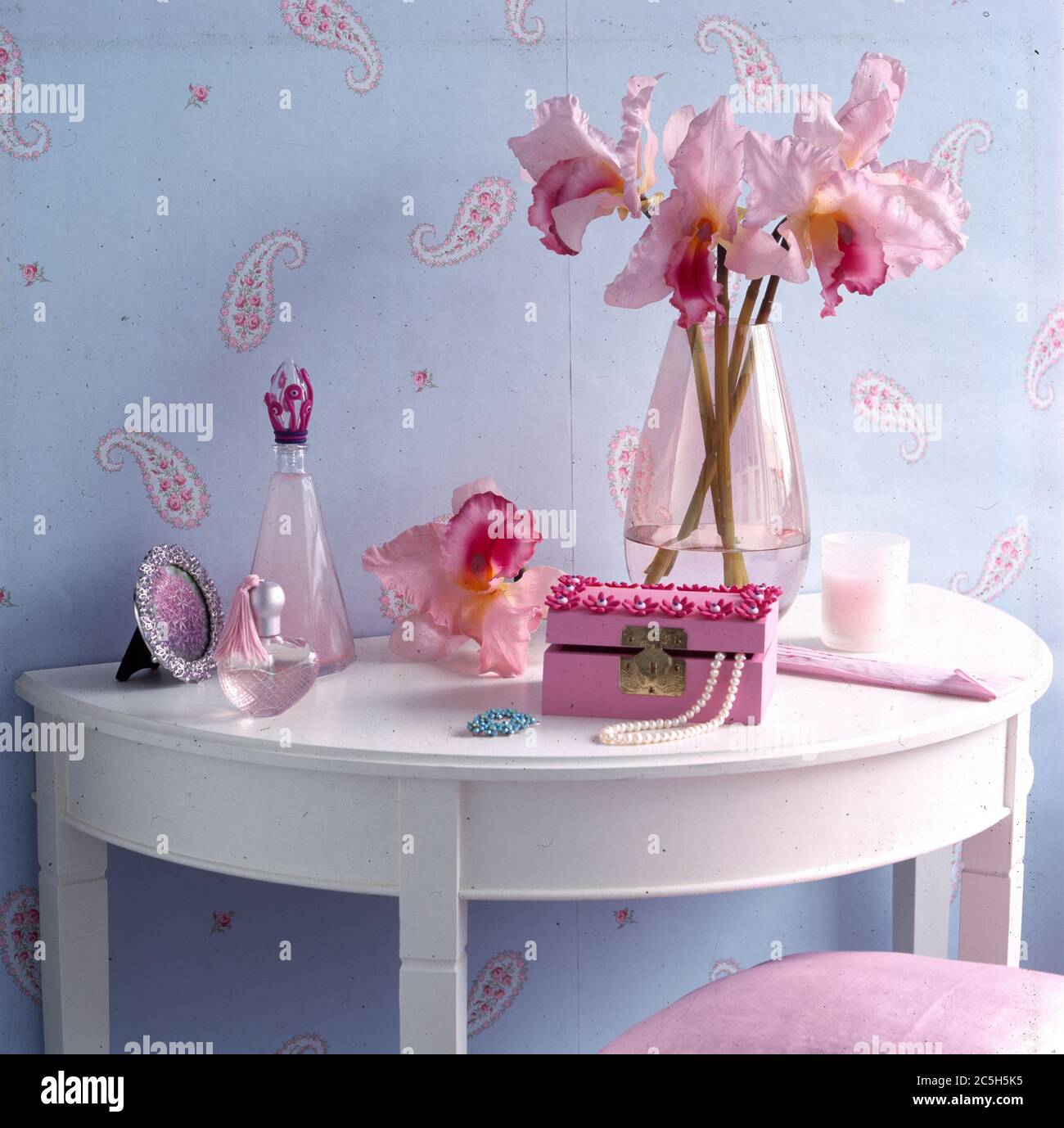 White painted table with pink jewellery box, flowers and perfume bottles. Stock Photo