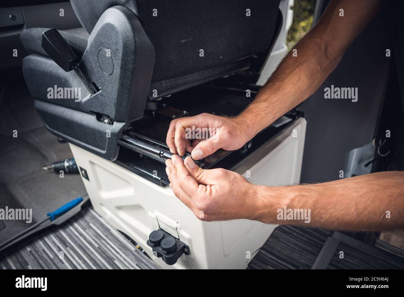 Close up of hands working on a seat inside a van Stock Photo