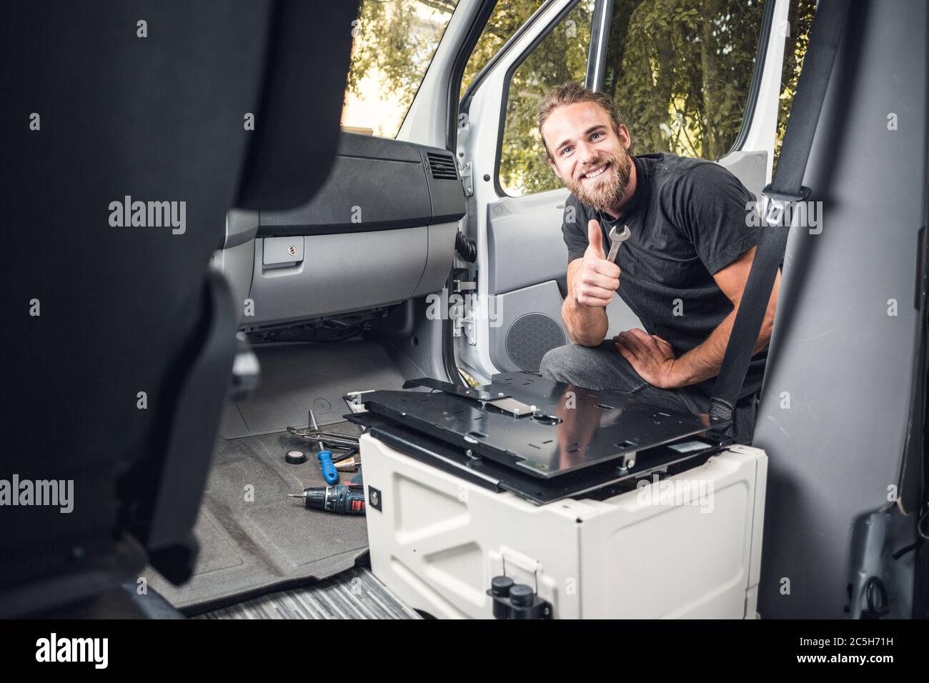Smiling man working inside his camper van Stock Photo