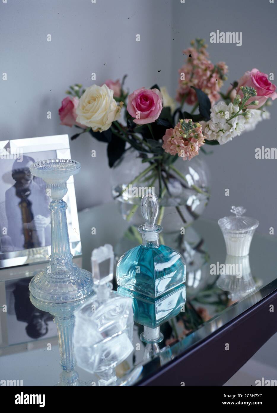 Dressing table with glass perfume bottles and vase of flowers Stock