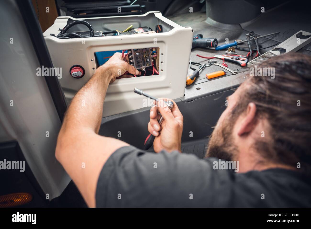 Man installing electrical equipment in his DIY camper van Stock Photo