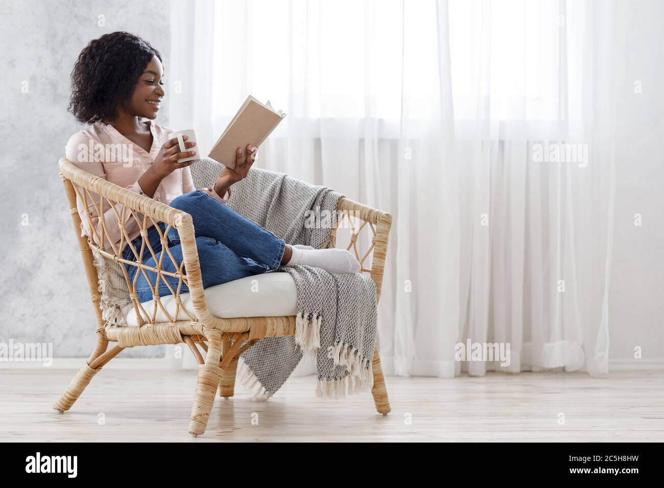 Home Leisure. Happy black girl reading book and drinking coffee in ...