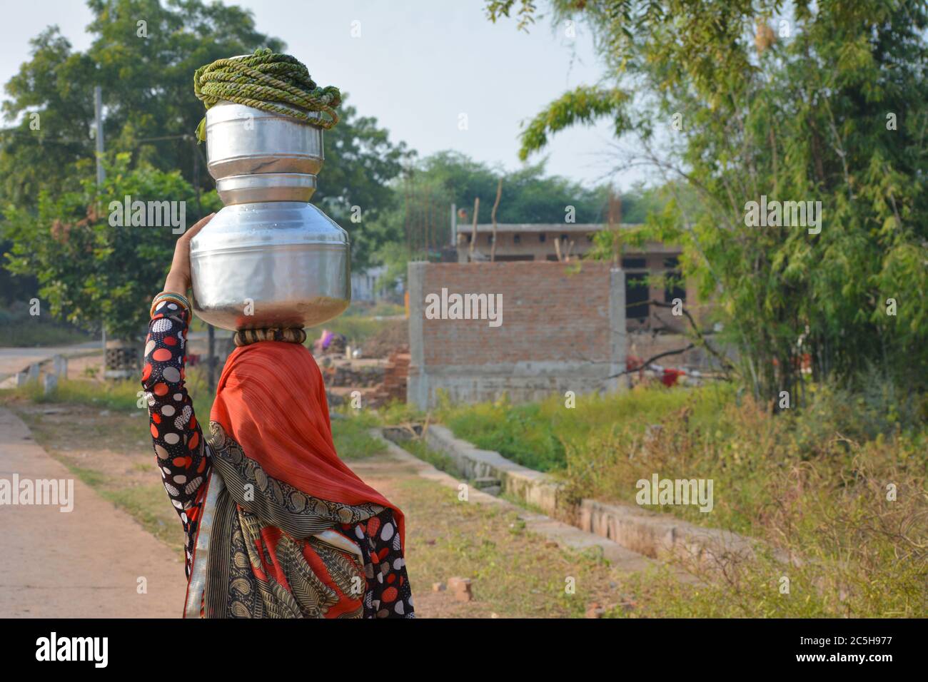 TIKAMGARH, MADHYA PRADESH, INDIA - NOVEMBER 12, 2019: An unidentified indian village woman carry water on their heads in traditional pots from well. Stock Photo