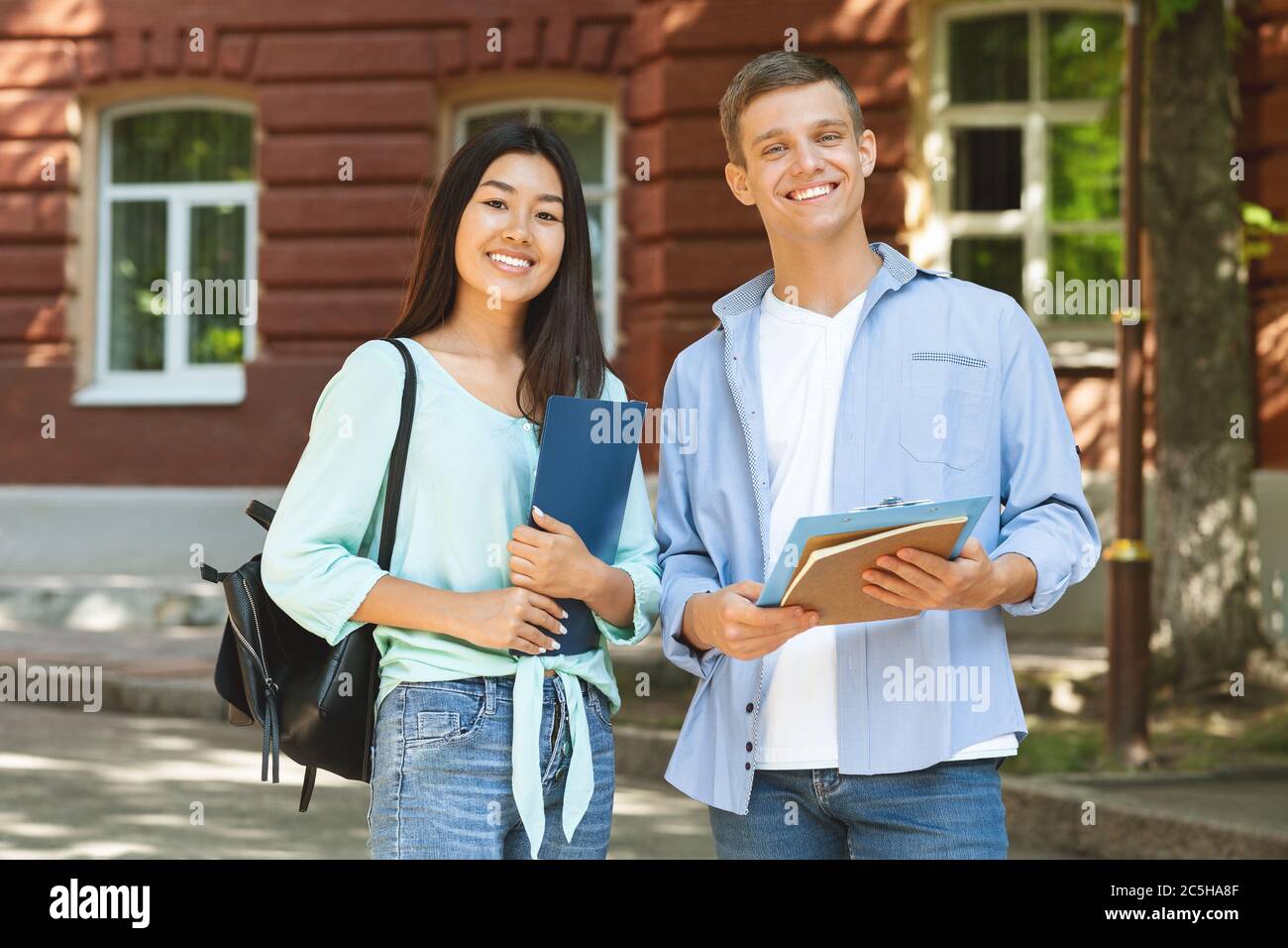 Portrait of smiling multiethnic students posing outdoors at campus after classes Stock Photo