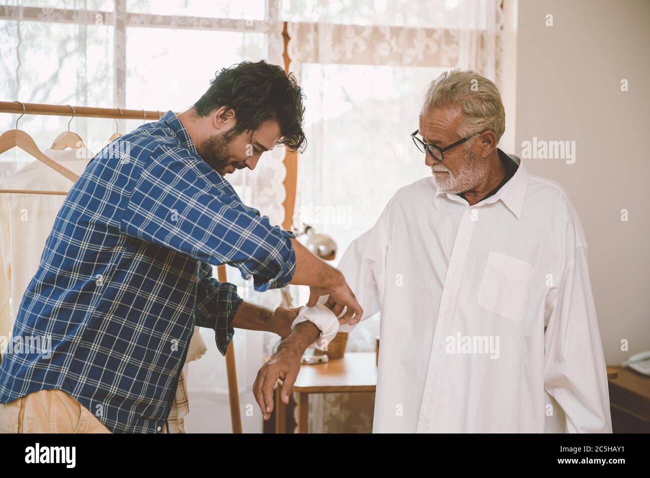 Son helped his father dressing cloth for holiday travel hang out lovely, family stay and care together concept. Stock Photo