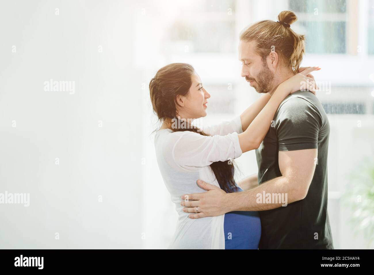 Pregnant woman wife standing, embracing the husband, looking together with love and connection, showing the warmth of couple lovers Stock Photo