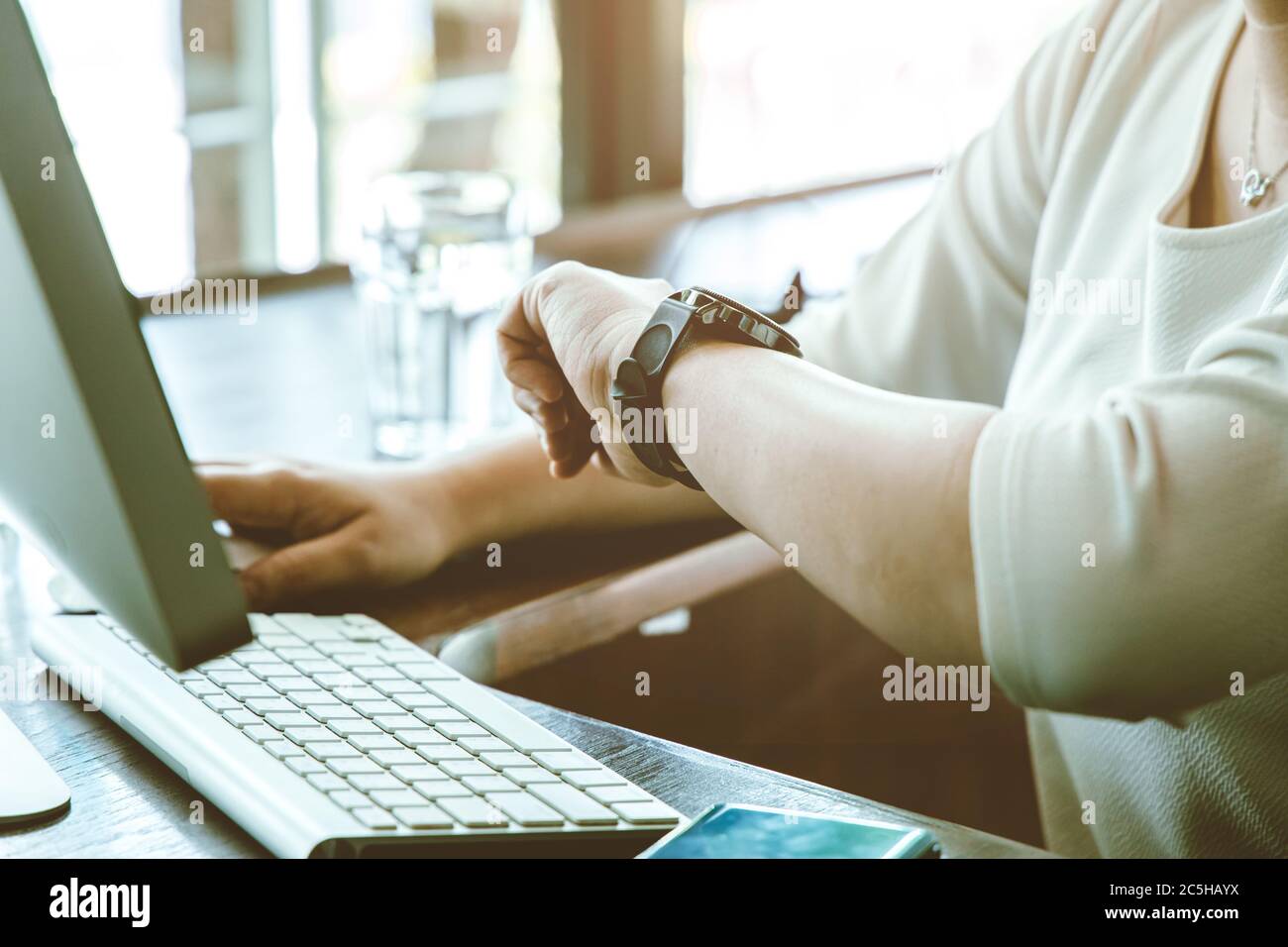 Businesswoman working on desk looking check meeting time on her wrist watch for schedule remind. Stock Photo