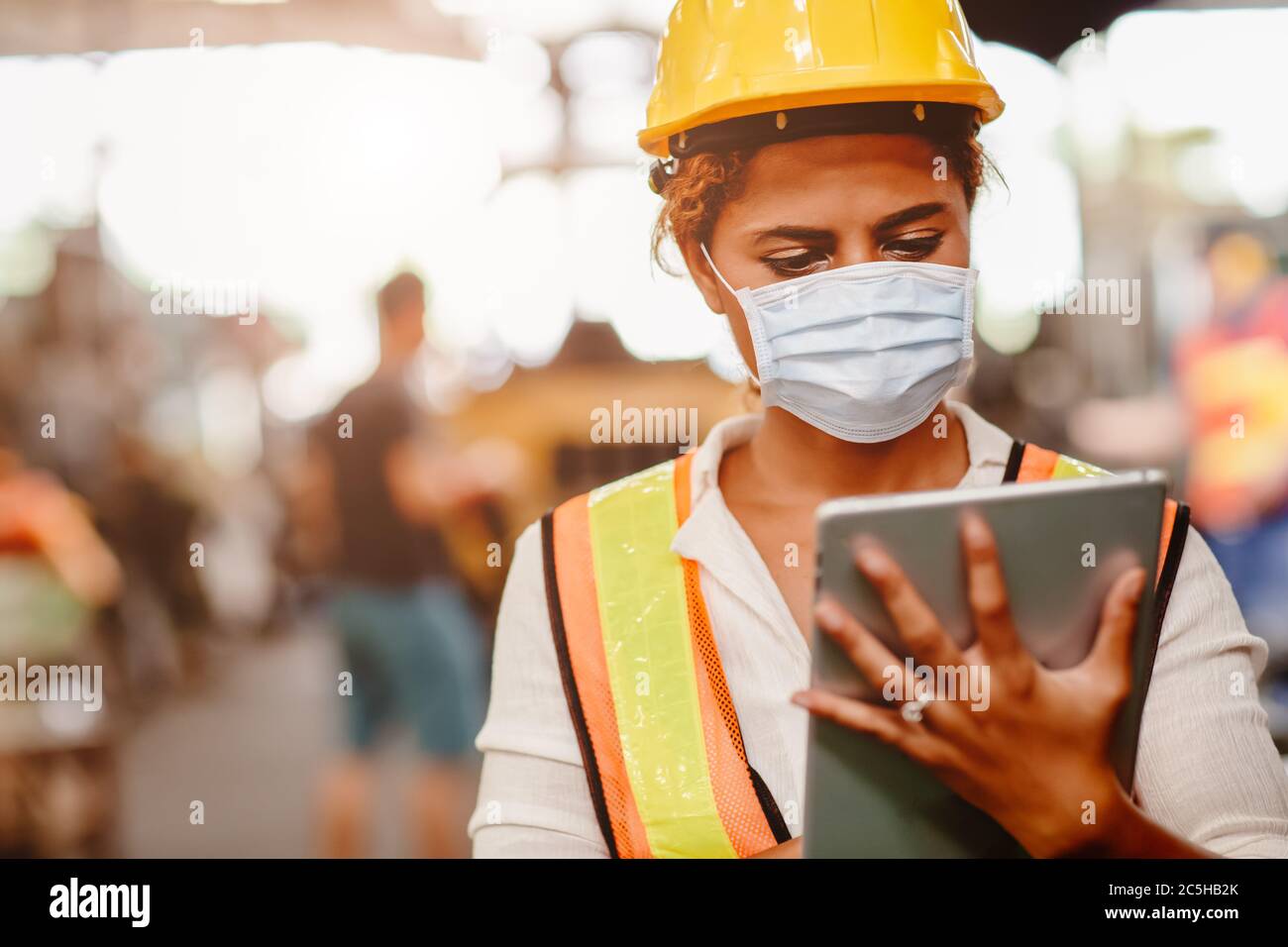 African American black women teen worker wearing face shield or disposable face mask during working in factory for prevent spreading of Coronavirus(Co Stock Photo