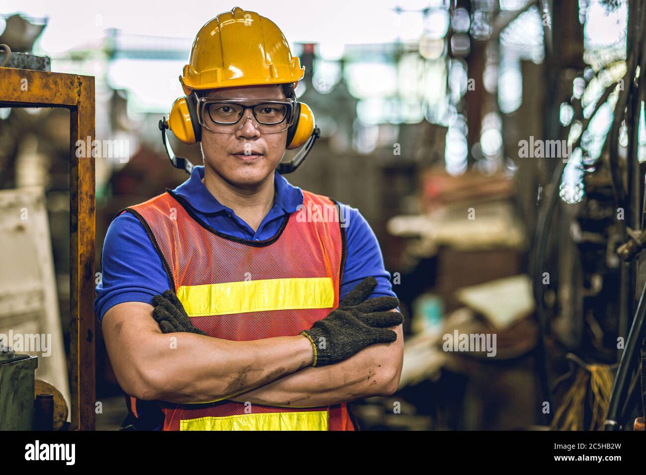 Asian Professional worker standing arm cross in heavy industry working in factory production line process with eyes and ears safety. Stock Photo