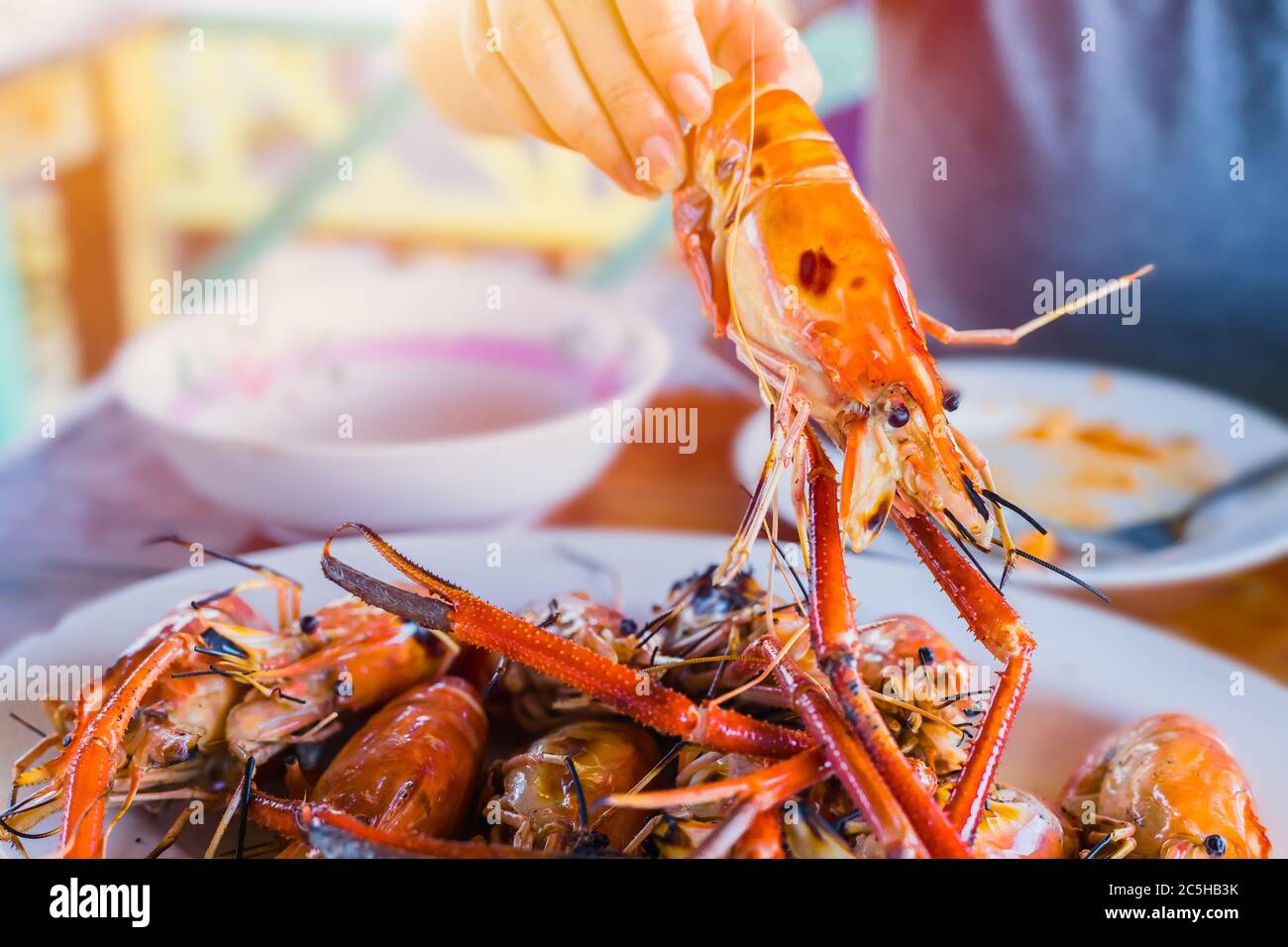 Asian Thai people eating grilled giant river prawn shrimp bbq with spicy sweet and sour seafood dipping sauce yummy popular food in Thailand. Stock Photo