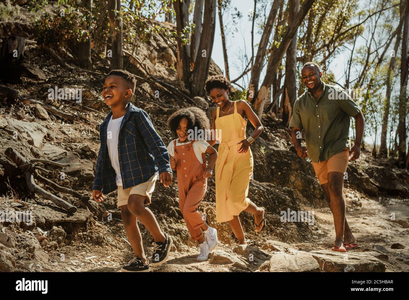 Young family enjoying their holidays in a national park. African family walking down a mountain trail and having fun. Stock Photo