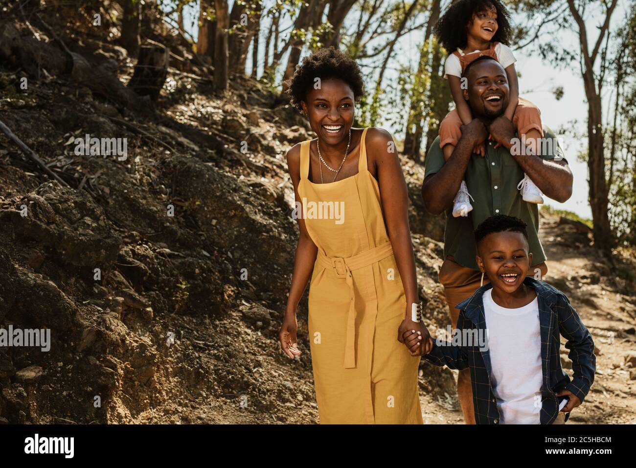 Cheerful family walking down a mountain trail. Parents and two kids hiking in national park. Stock Photo