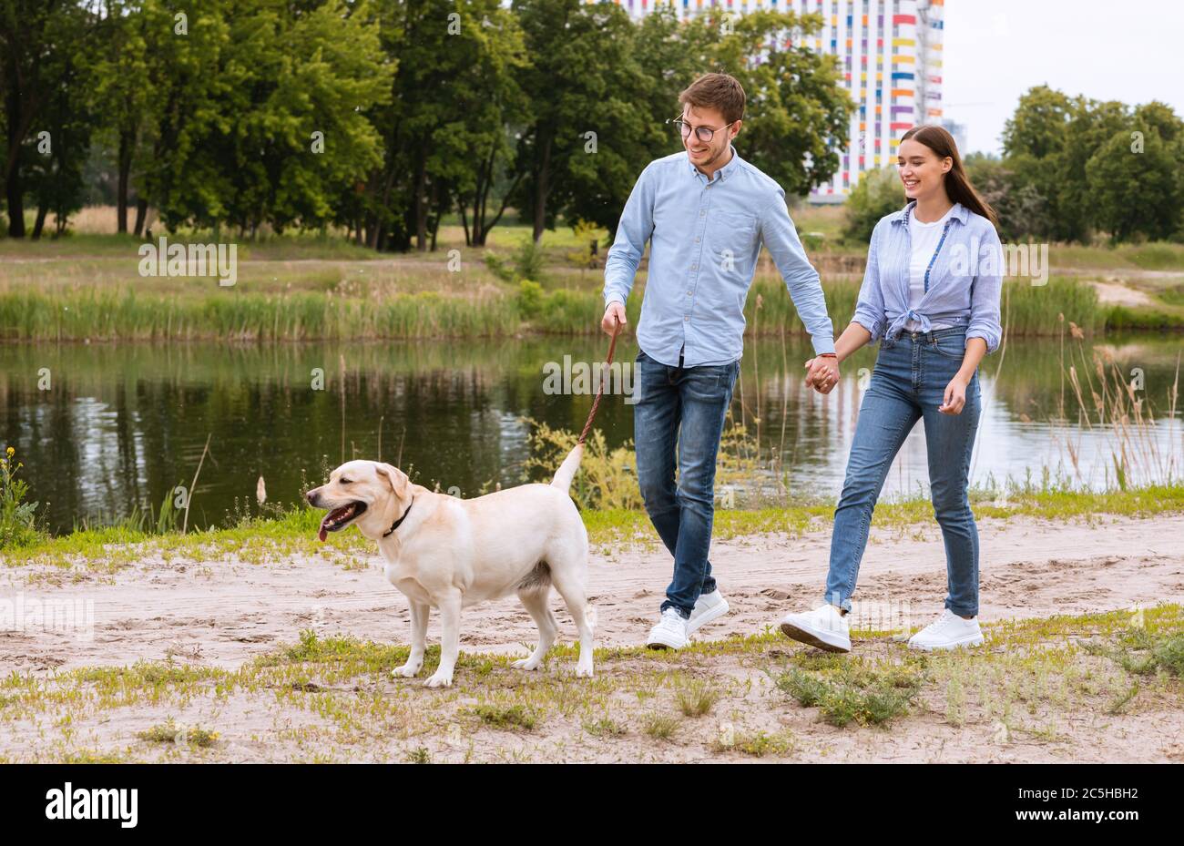 Portrait of happy young couple walking with their dog Stock Photo - Alamy
