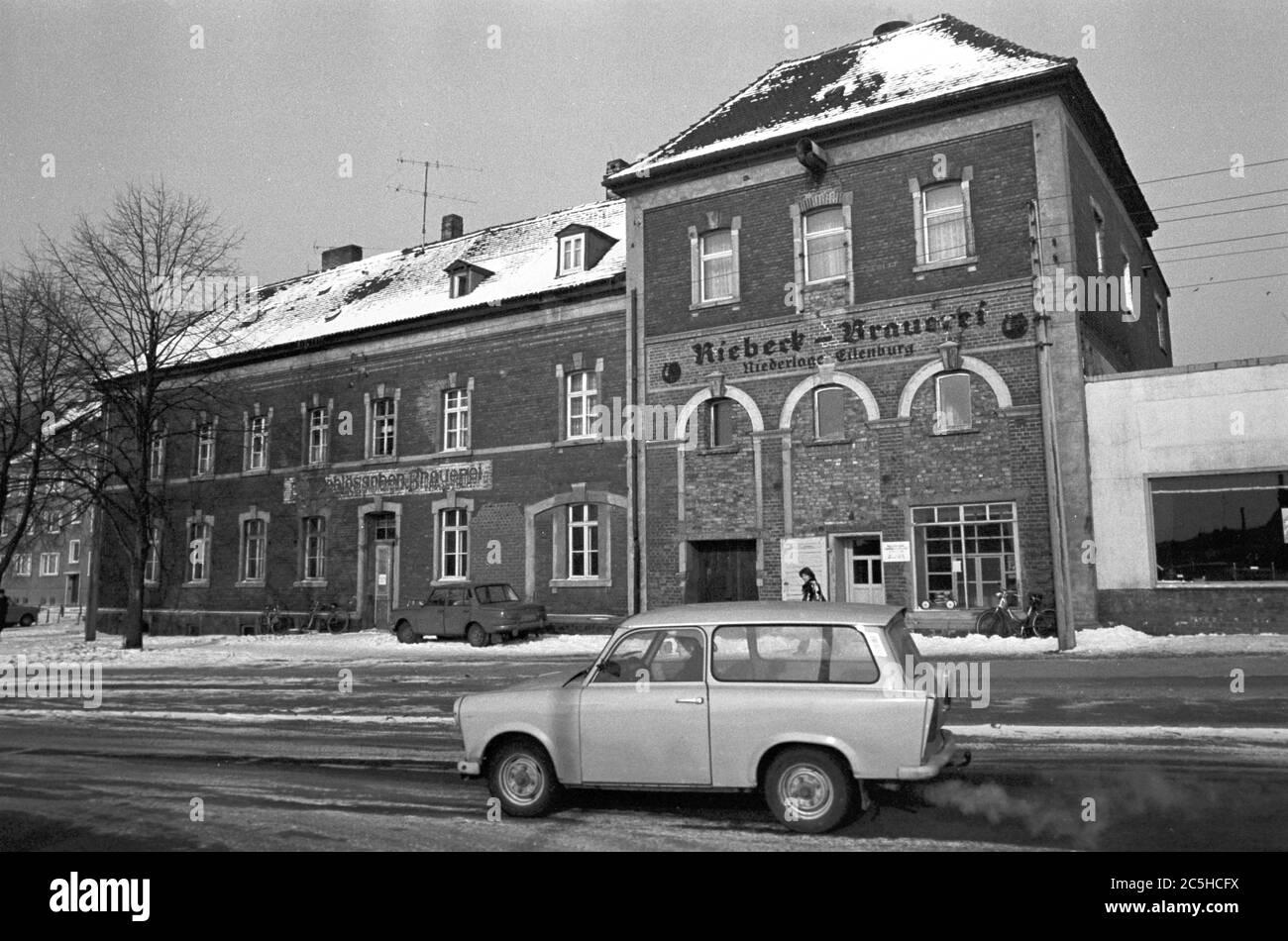 30 November 1984, Saxony, Eilenburg: The historic buildings of the former (Leipzig) Riebeck brewery (defeat of Eilenburg) were given a new 'purpose' - a lawnmower and bicycle workshop - in the mid-1980s through structural interventions and changes. A Wartburg stands in front of it, a Trabant drives by. Exact date of recording not known. Photo: Volkmar Heinz/dpa-Zentralbild/ZB Stock Photo