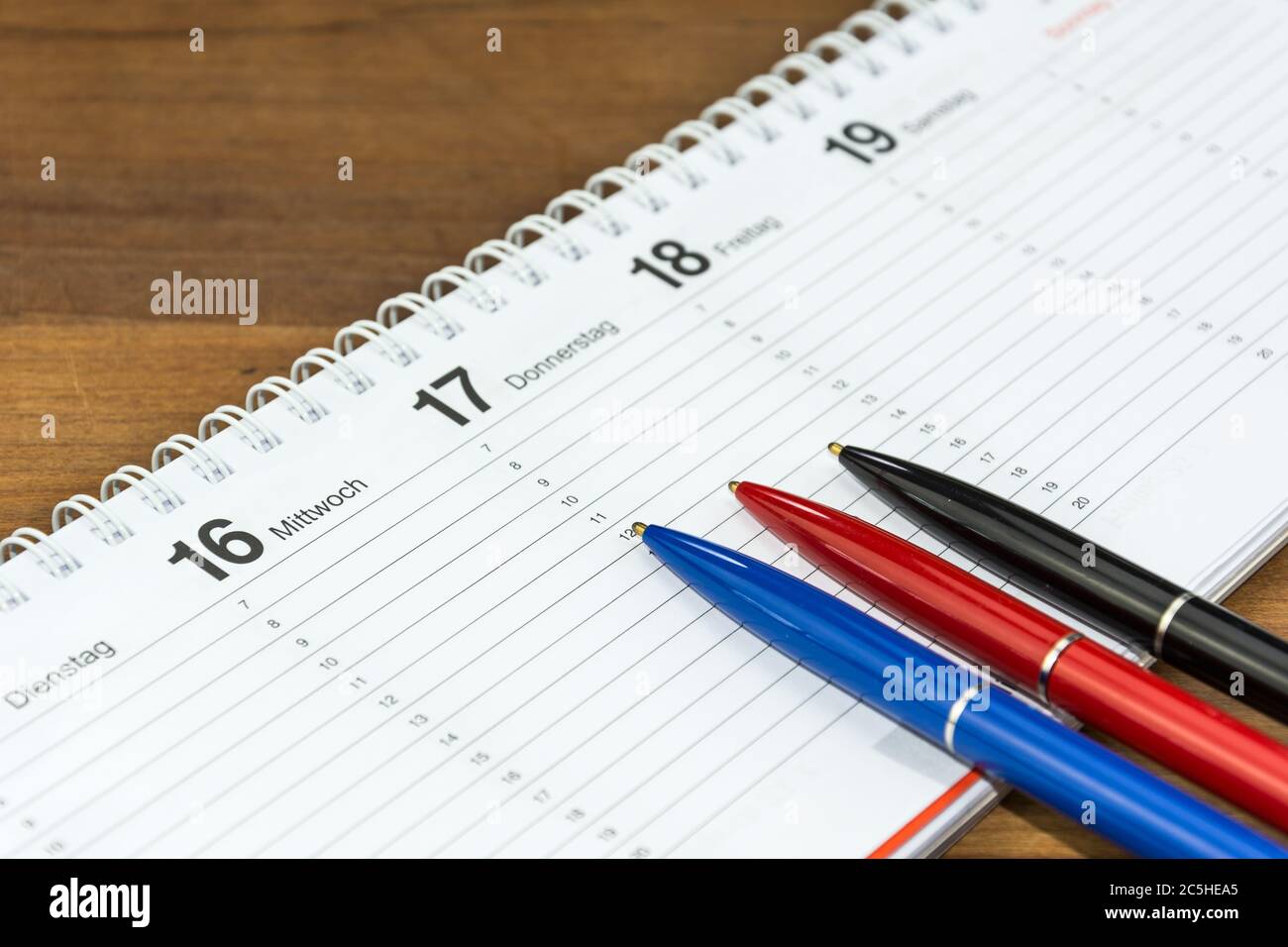 Three pens lying on schedule (with captions of the days of the week in German) Stock Photo