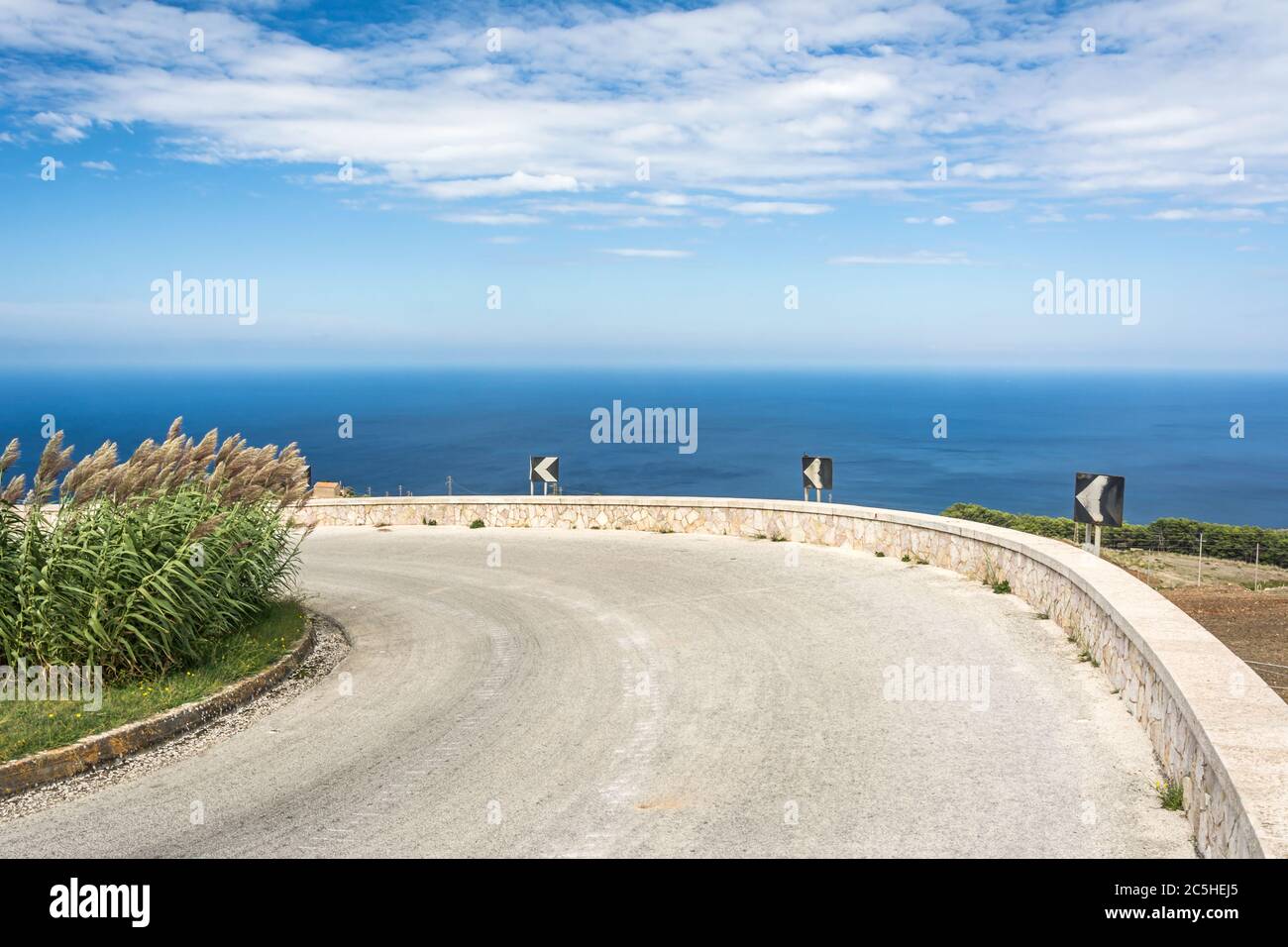 Scenic curvy coastal road with blue ocean in the background Stock Photo