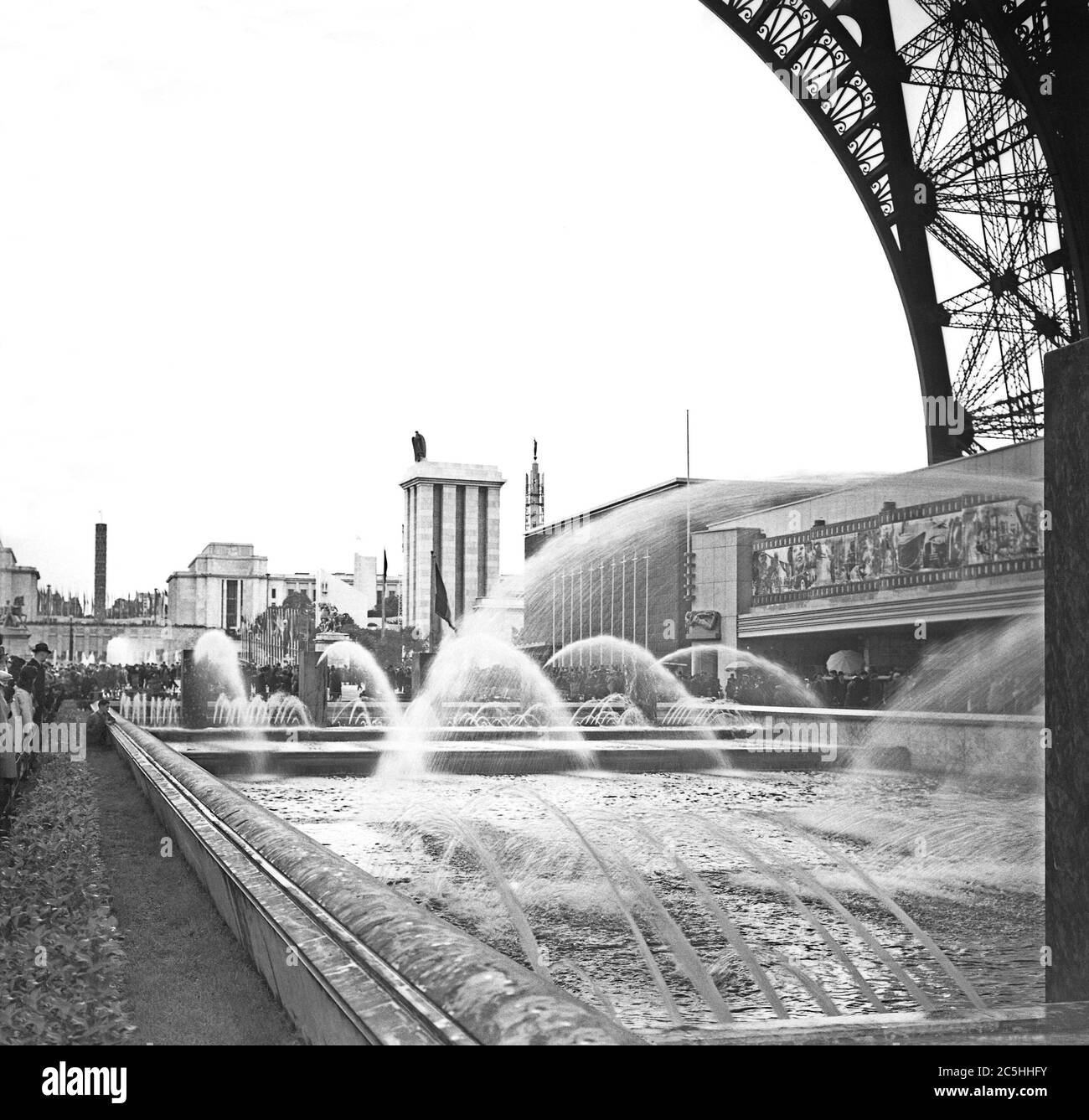 A view of the 1937 Expo (World's Fair or Exposition) held in Paris, France – here looking north from below the Eiffel Tower. Behind the fountains on the right is the Cinema and Photography pavilion, behind which is the modest Belgian pavilion. Beyond, across the River Seine in the 'Sections Etrangeres' of the site is the German pavilion. Hitler's architect Albert Speer designed the German pavilion. Speer's pavilion was fronted by the tall tower crowned with the symbols of the Nazi state, the eagle and the swastika. Stock Photo
