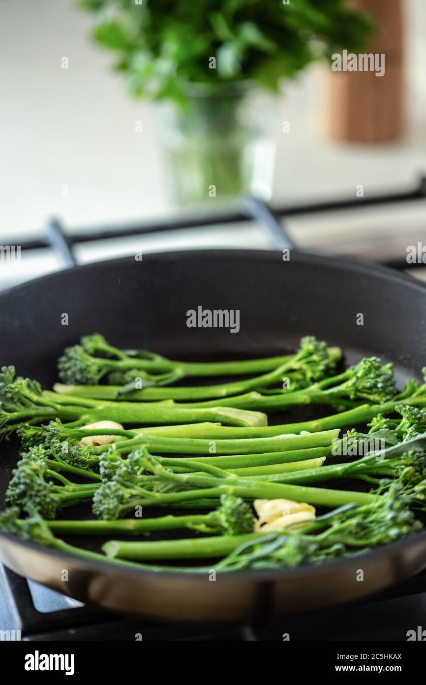 Cooking broccolini in a fried pan. Angle view. Stock Photo