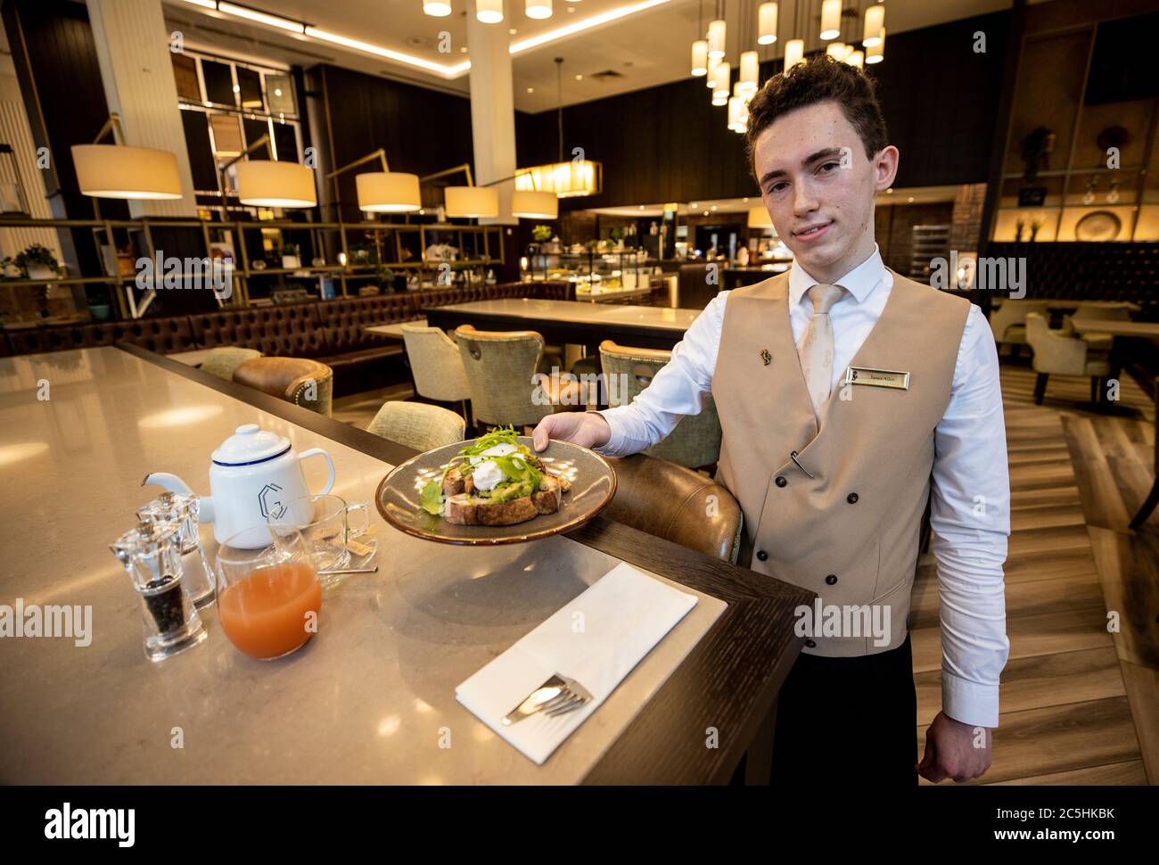 James Allen serving eggs Benedict in the Grand Cafe at the Grand Central Hotel in Belfast as lockdown eases allowing hotels and bars to reopen. Stock Photo