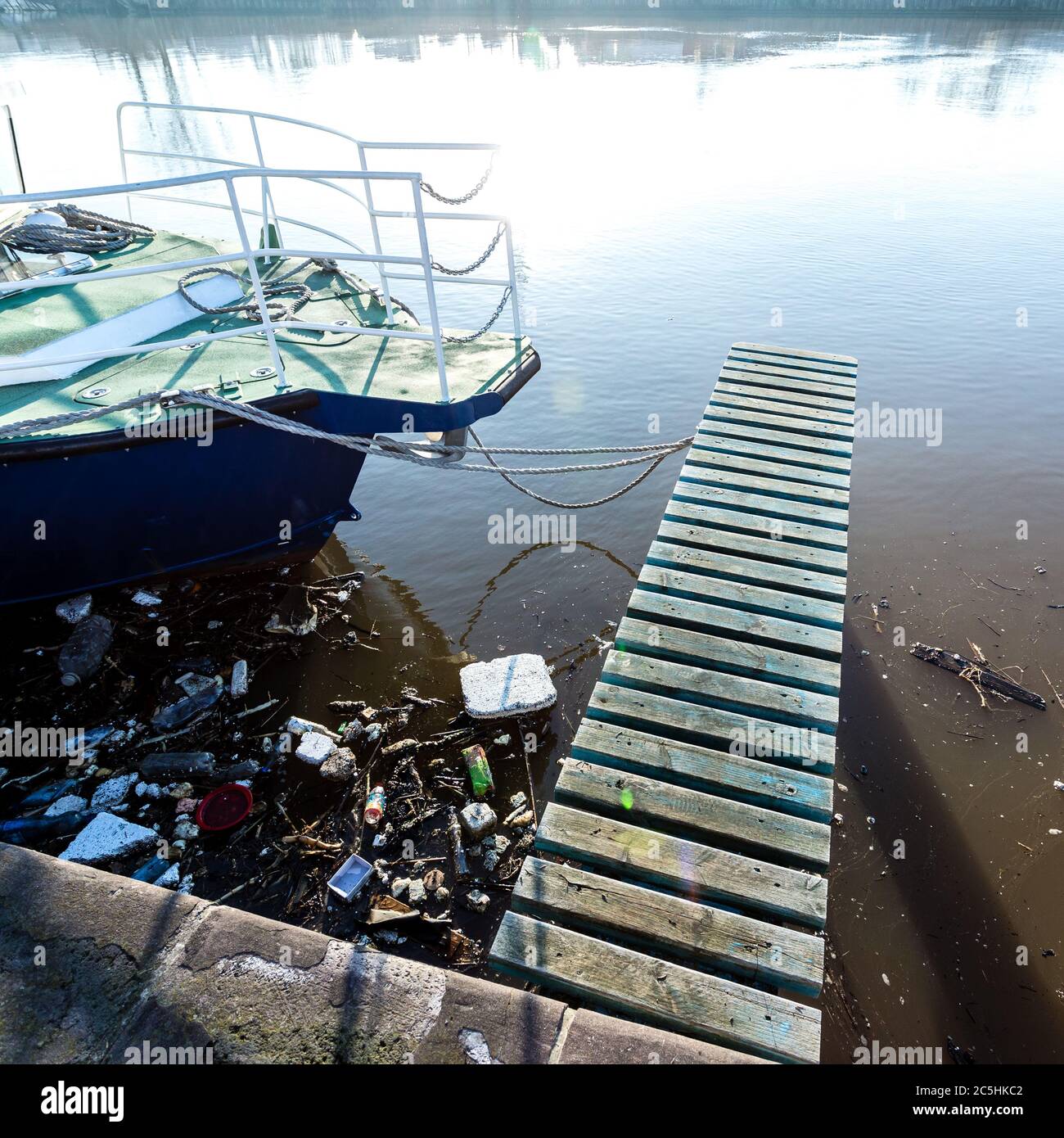 Plastic bottles, packages, trash in river near yacht. Illegal garbage