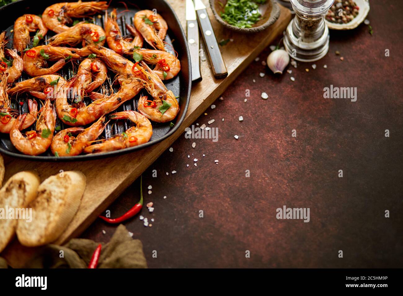 Grilled prawns in cast iron grilling pan with fresh lemon, parsley