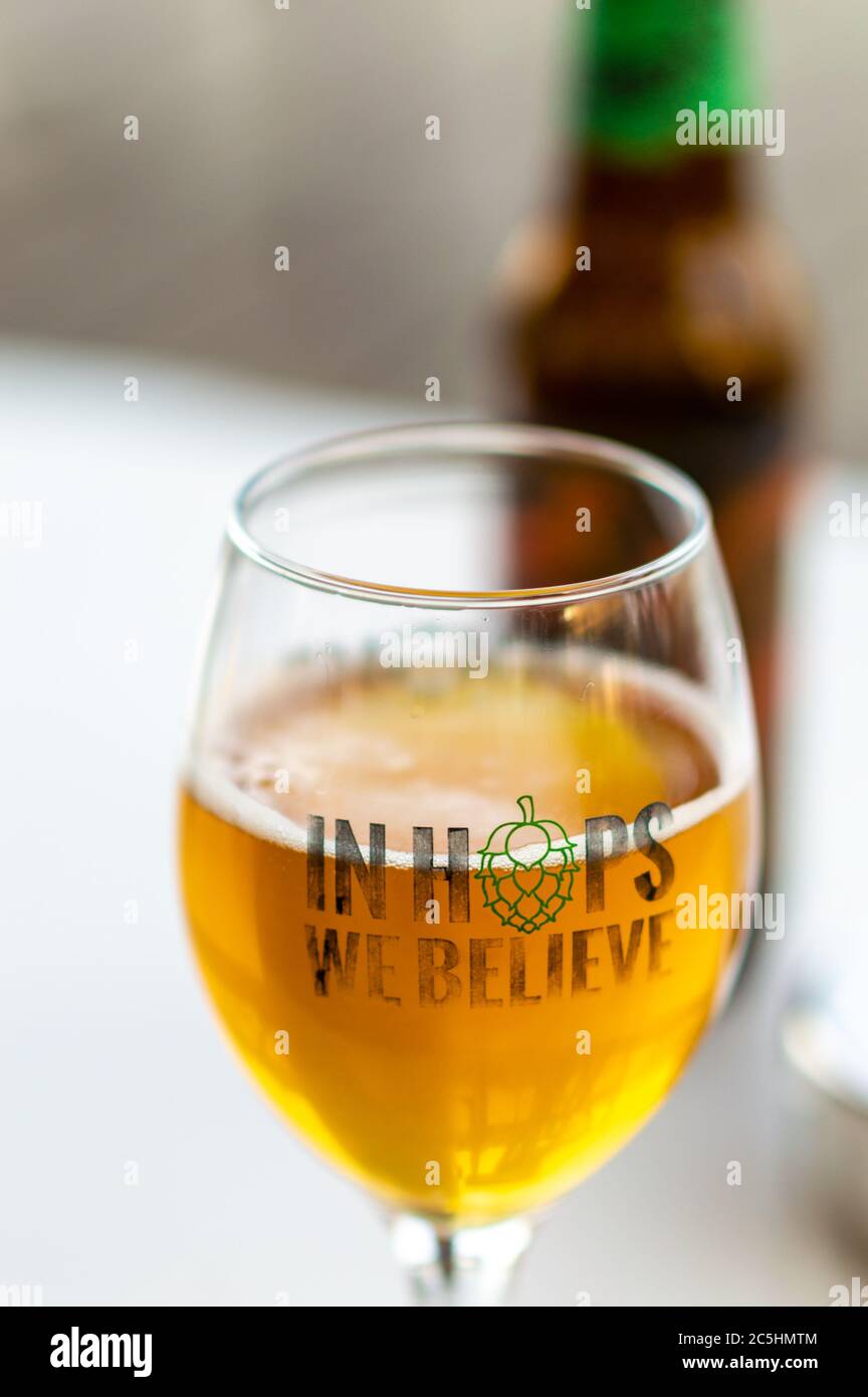 Glass of craft beer in selective focus with 'In Hops We Believe' text Stock Photo
