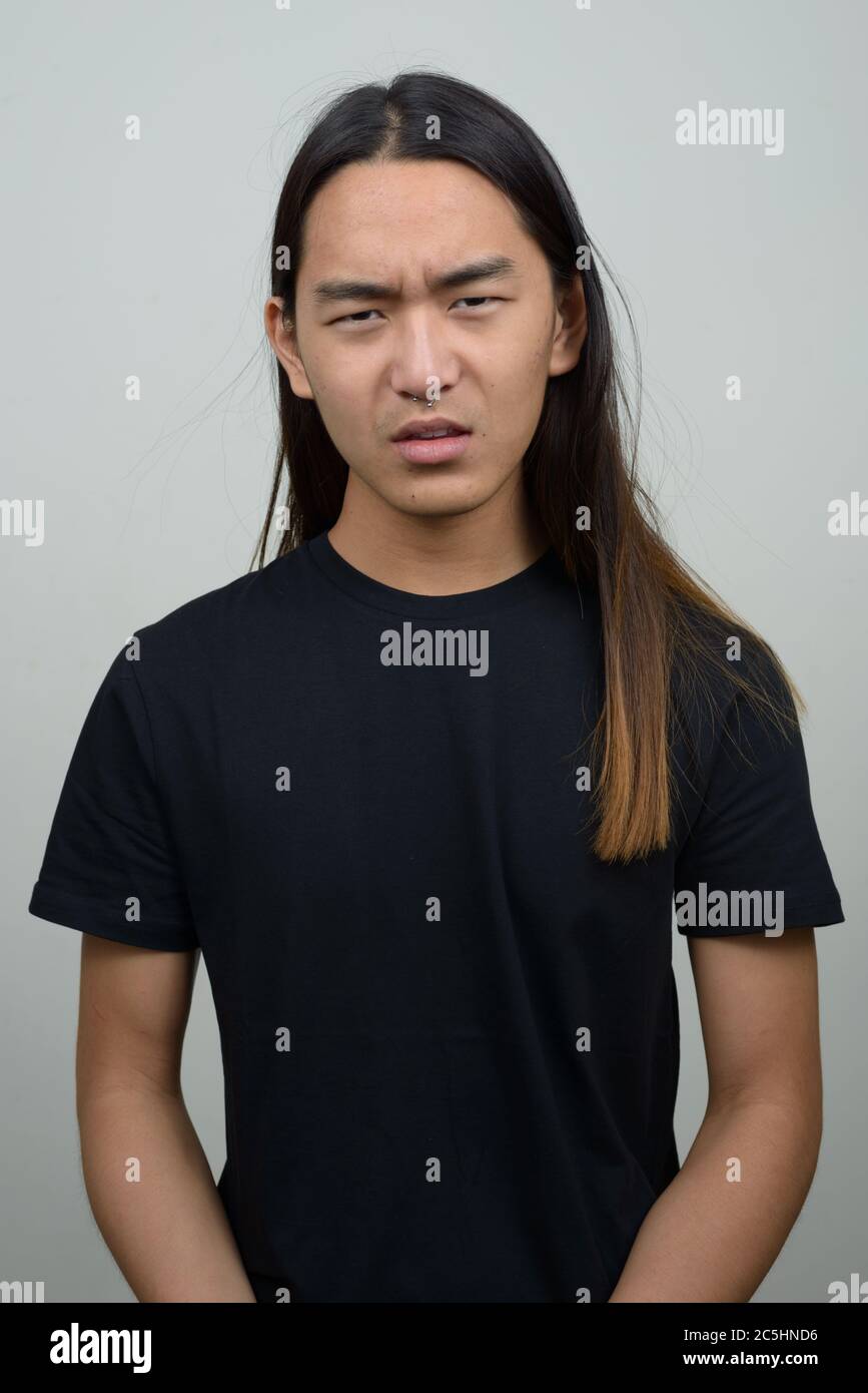 Stressed young Asian man with long hair looking angry Stock Photo - Alamy