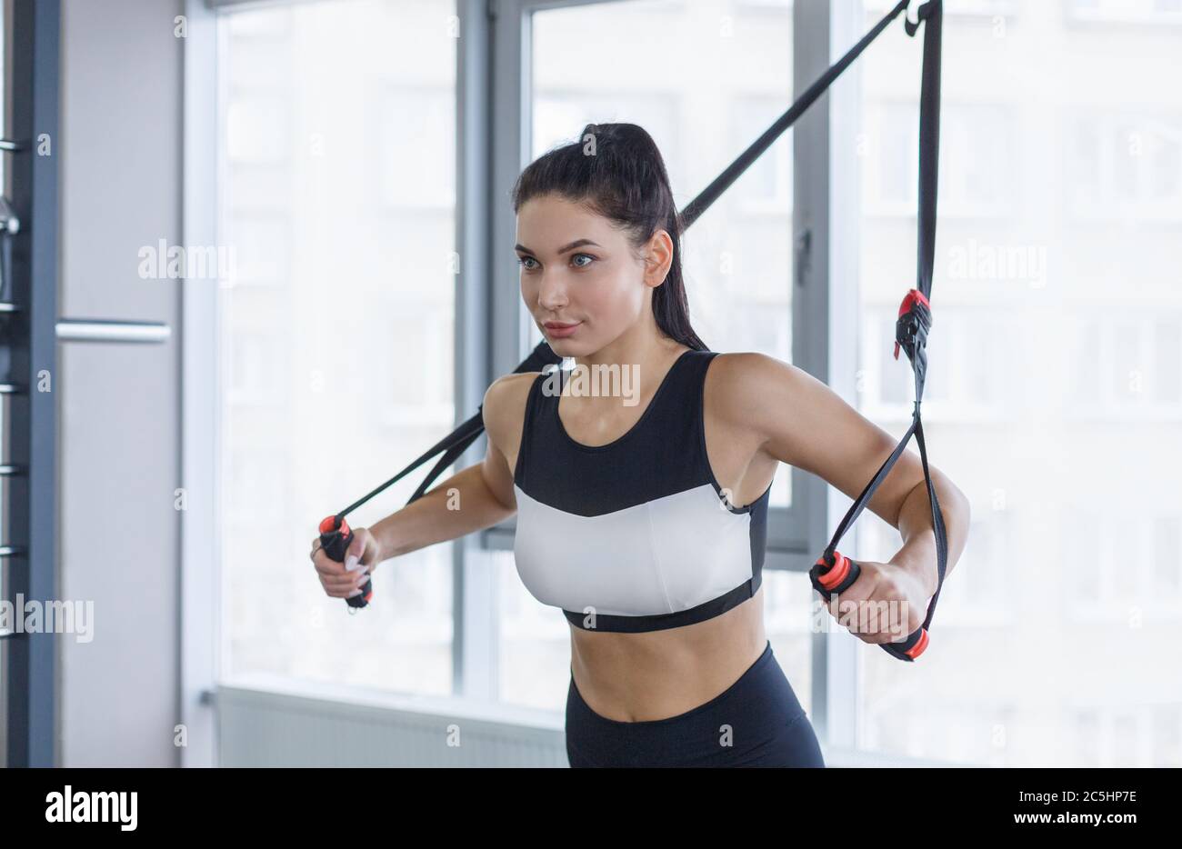 Strong girl working out with cable machine, lifting weights at gym