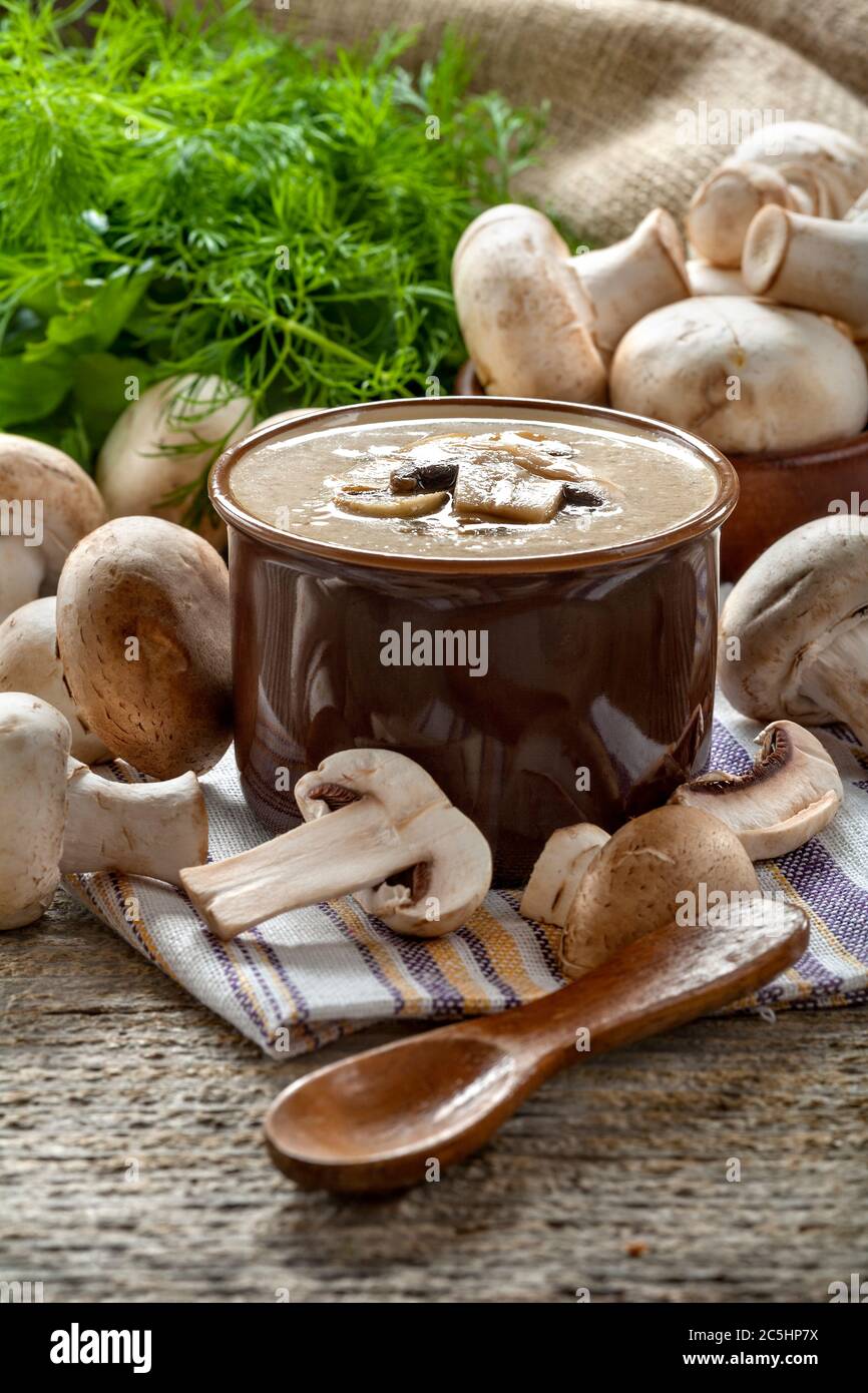 Cream soup with mushrooms champignon in a bowl, vintage style composition on a rustic wooden table. Stock Photo