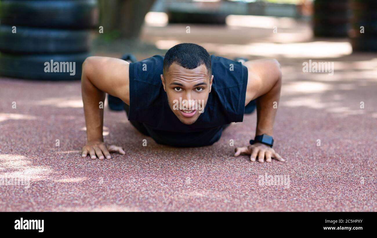 Strong African Anerican sportsman doing push up exercises after jogging ...