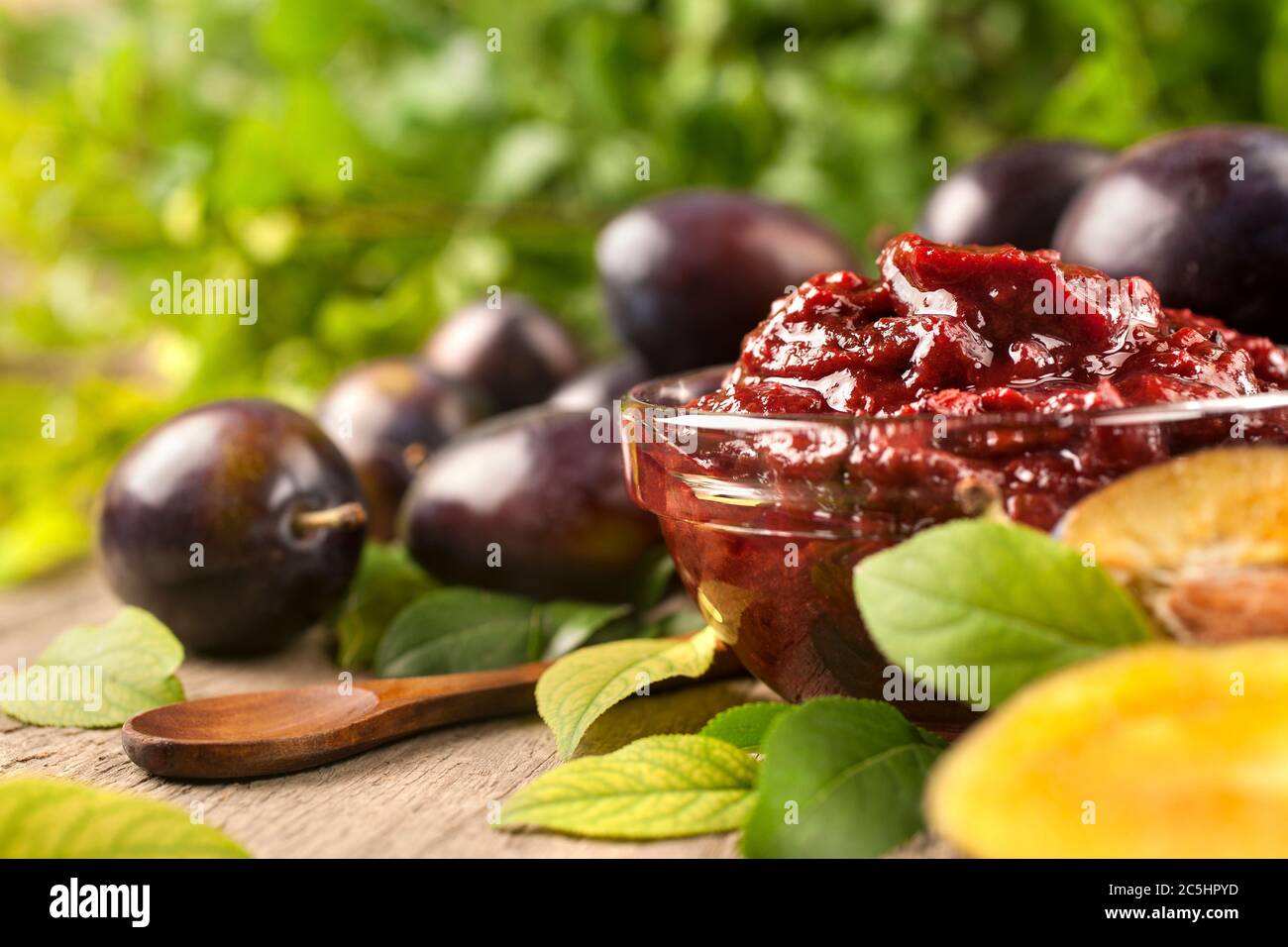Jam of healthy organically grown plums with plum fruits on wooden table background. Close up, side view, high-resolution product image. Stock Photo