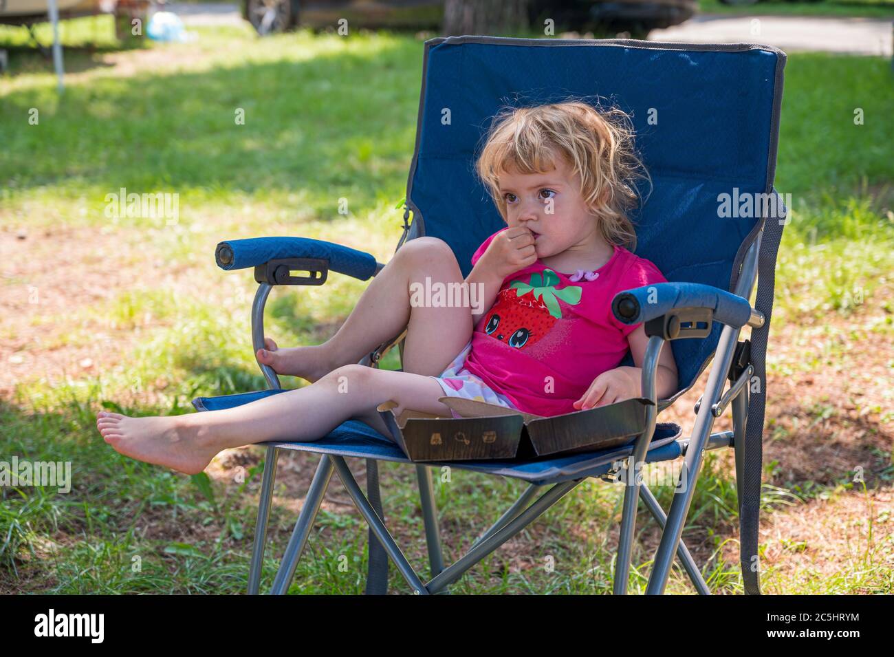 Cute blonde girl sitting at the table in camping resort Stock Photo - Alamy