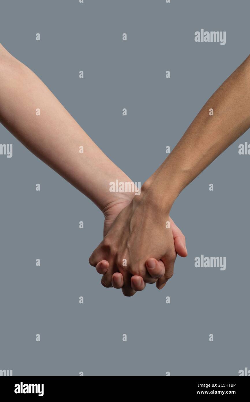 Close-up of light-skinned and dark-skinned people holding hands Stock Photo