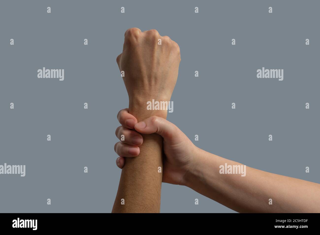Close-up of light-skinned hand clenching dark-skinned wrist Stock Photo