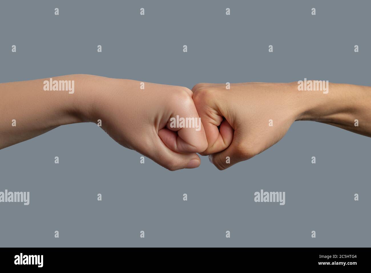 Close-up of light-skinned and dark-skinned fists bumping together Stock Photo