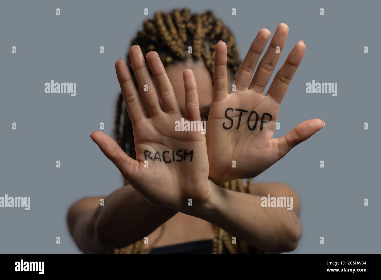 Young African American woman hiding her face with crossed palms, showing stop racism lettering Stock Photo
