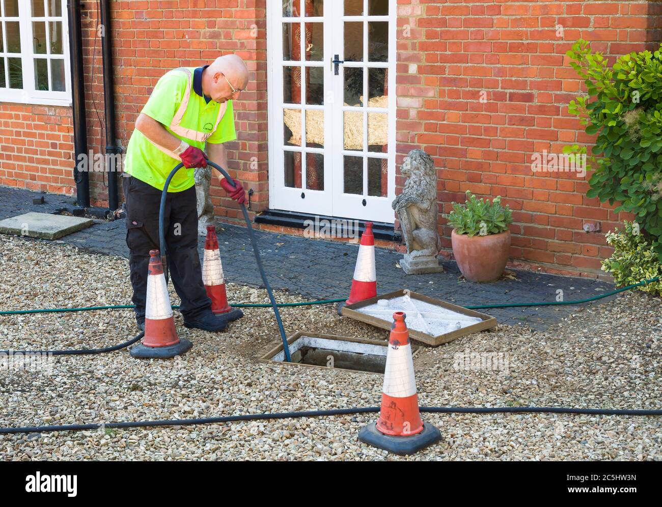 BUCKINGHAM, UK - August 07, 2015. Man jetting sewage drain outside house, drain cleaning company unblocking main sewage pipe, UK Stock Photo