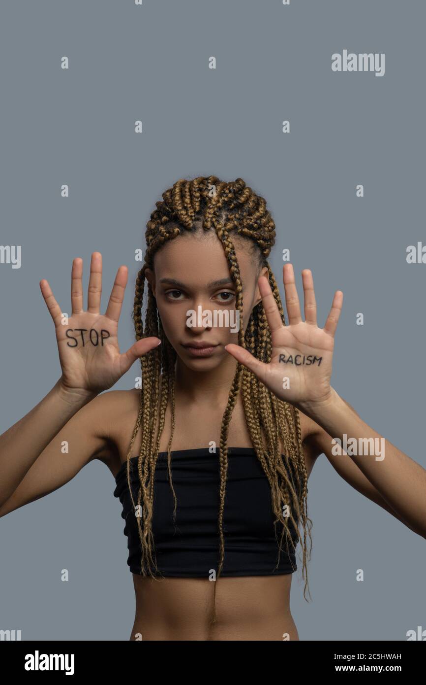 Young African American woman in black top holding her palms up with stop racism lettering Stock Photo