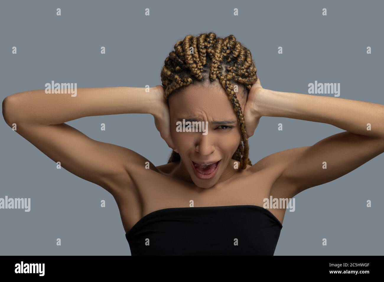 Devastated young African American woman closing her ears with hands, screaming Stock Photo