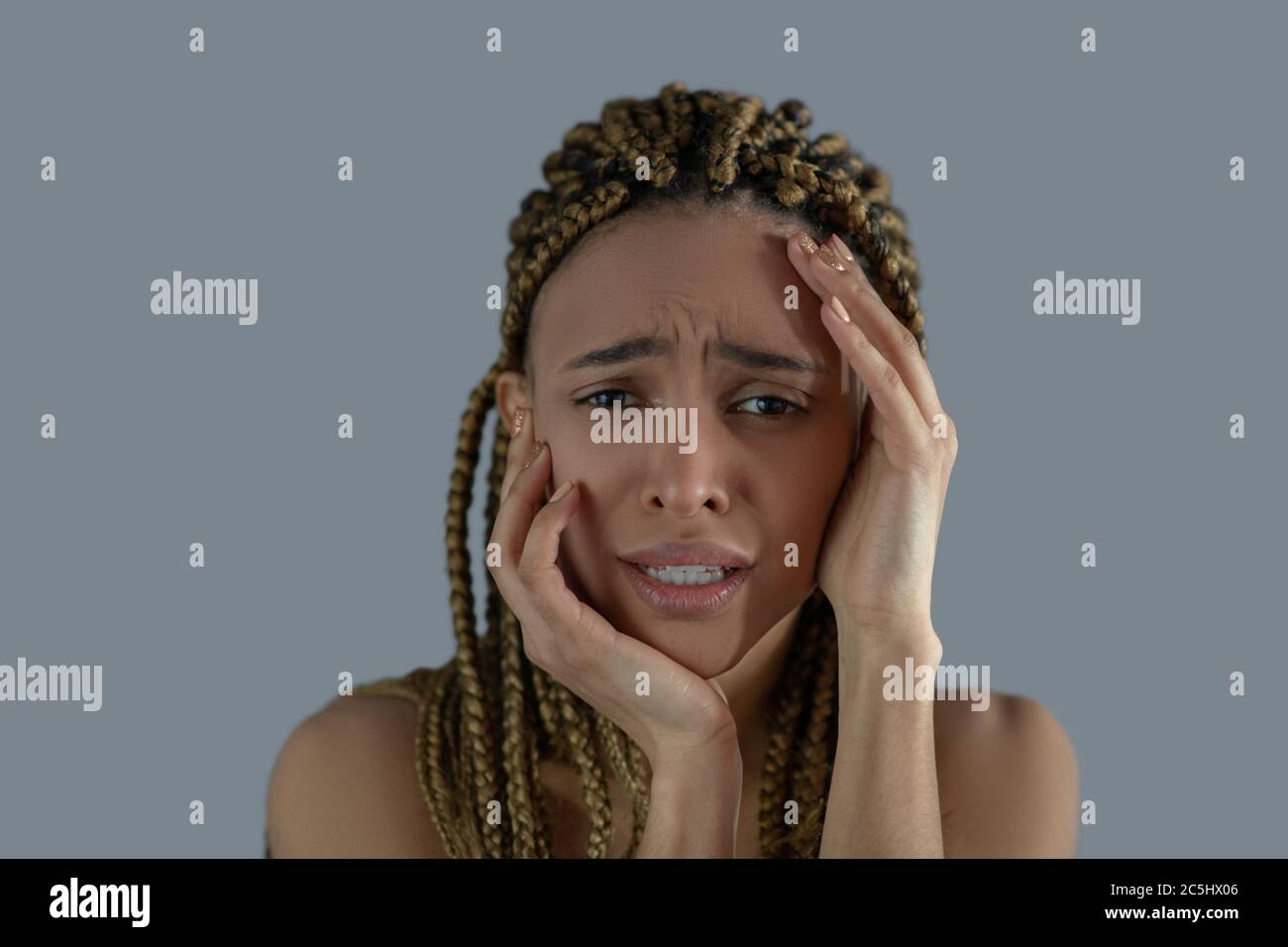 Devastated young African American holding her face with her hands, frowning with pain Stock Photo