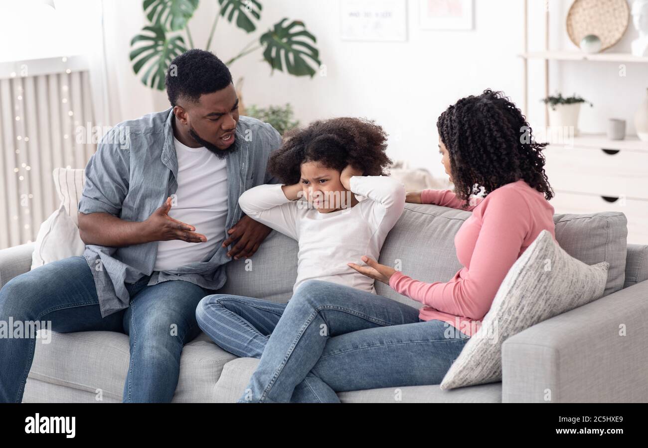 Annoyed Black Parents Scolding Stubborn Little Daughter At Home Stock Photo