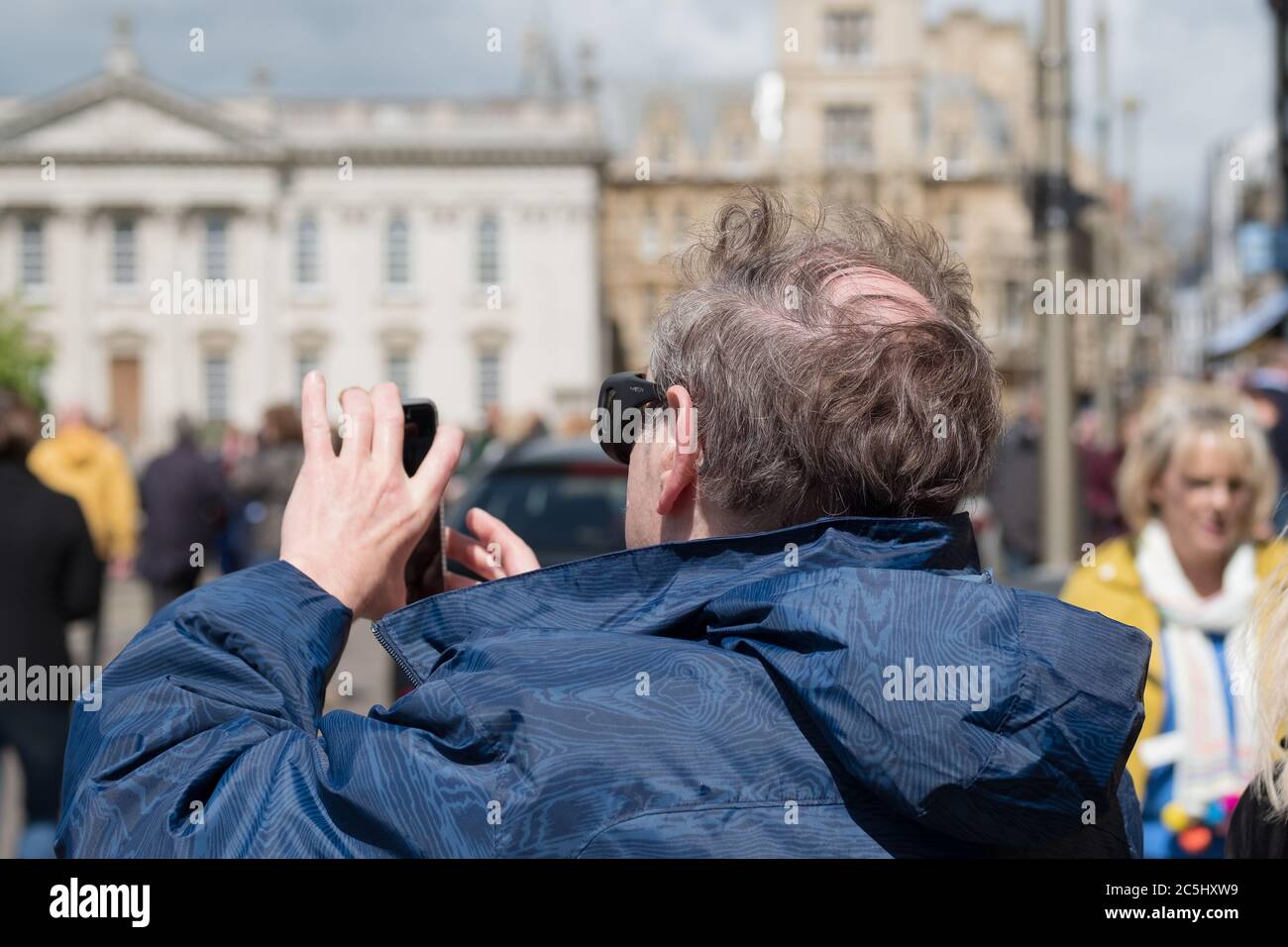 Shallow focus of the back of a man seen aiming his smartphone while taking a picture of a building in the famous english city. Stock Photo