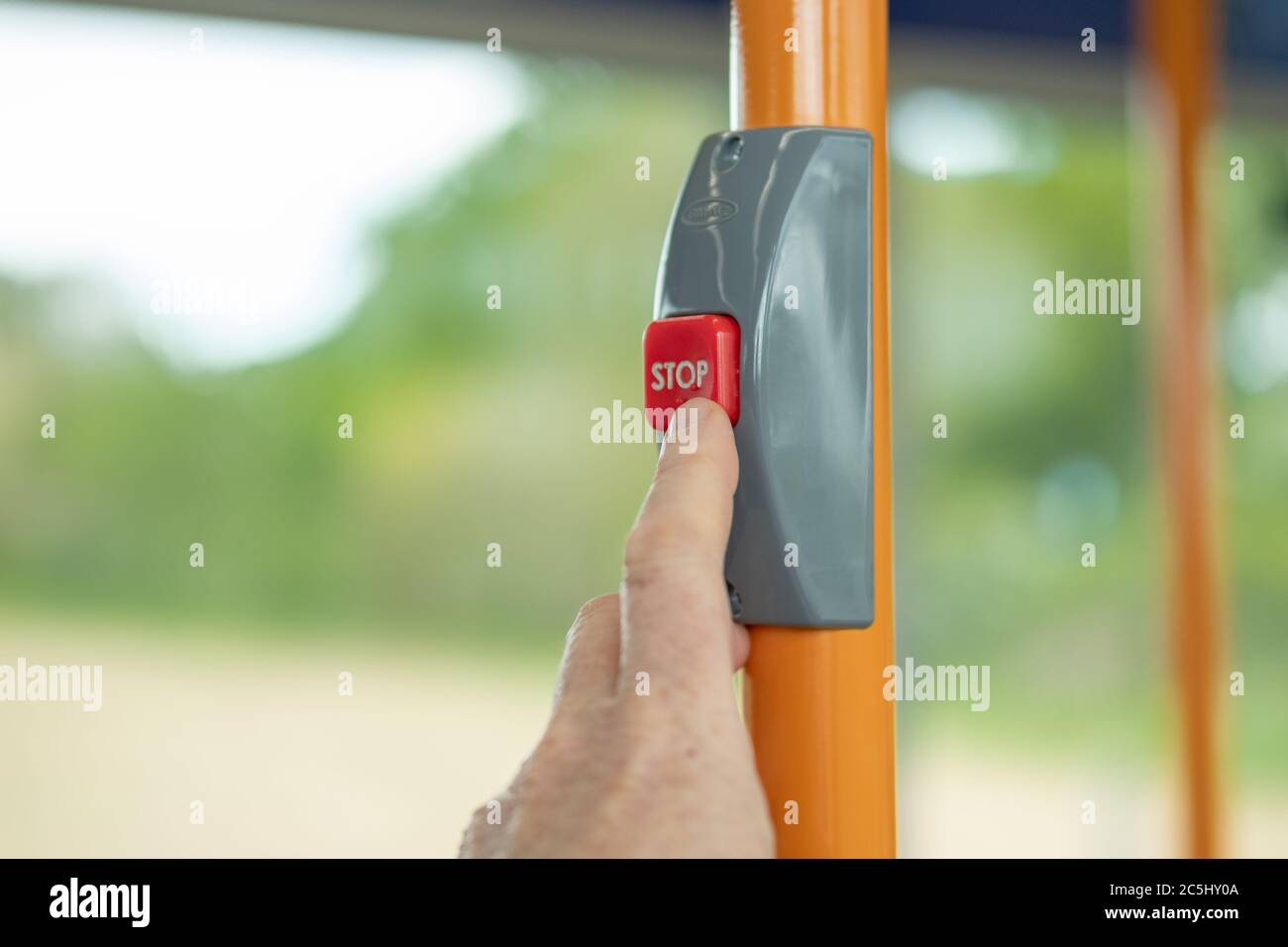 Adult commuter seen pressing a request stop button inside a public transport bus Stock Photo