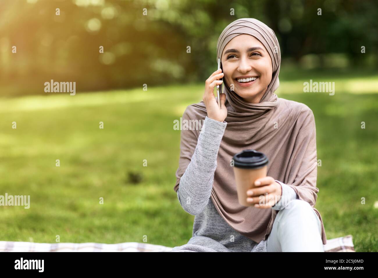 Happy muslim girl talking on phone and drinking coffee Stock Photo - Alamy