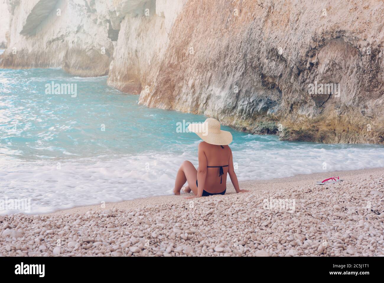 Young beautiful woman in swimsuit and hat relaxing on Navagio beach, Zakynthos island, Greece Stock Photo
