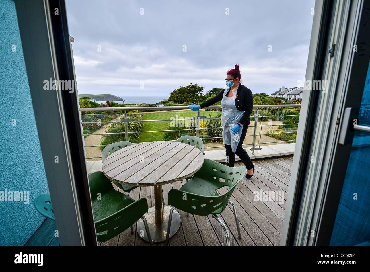 Head housekeeper Carolanne Rowe wears ppe as she cleans a balcony railing  in a hotel suite at St Moritz hotel and spa, Cornwall, during room  saintising in preparation ahead of reopening to