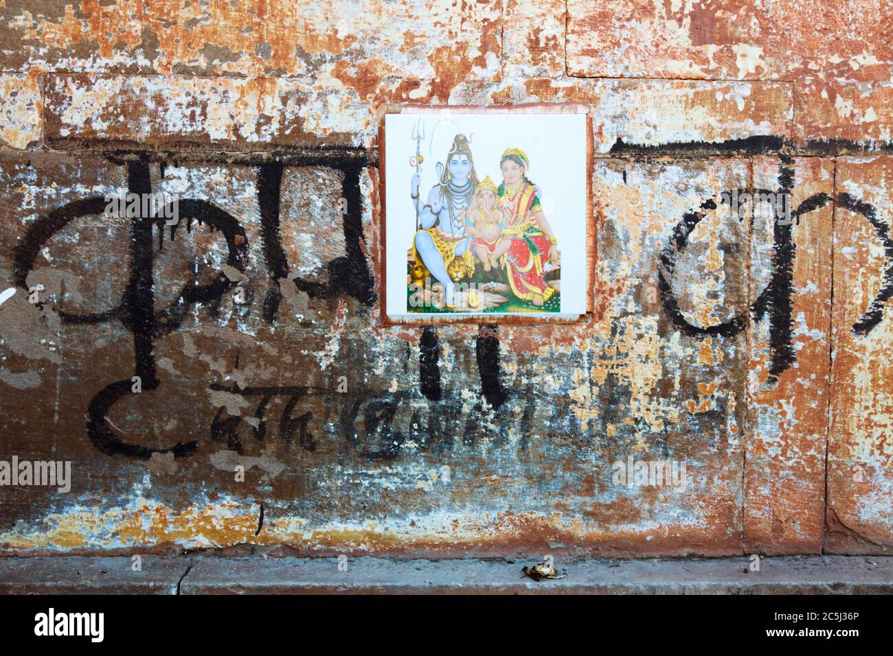 Varanasi, Uttar Pradesh, India : Close up of a weathered wall with Devanagari script and a tile depicting the gods Shiva, Parvati and Ganesh. Stock Photo
